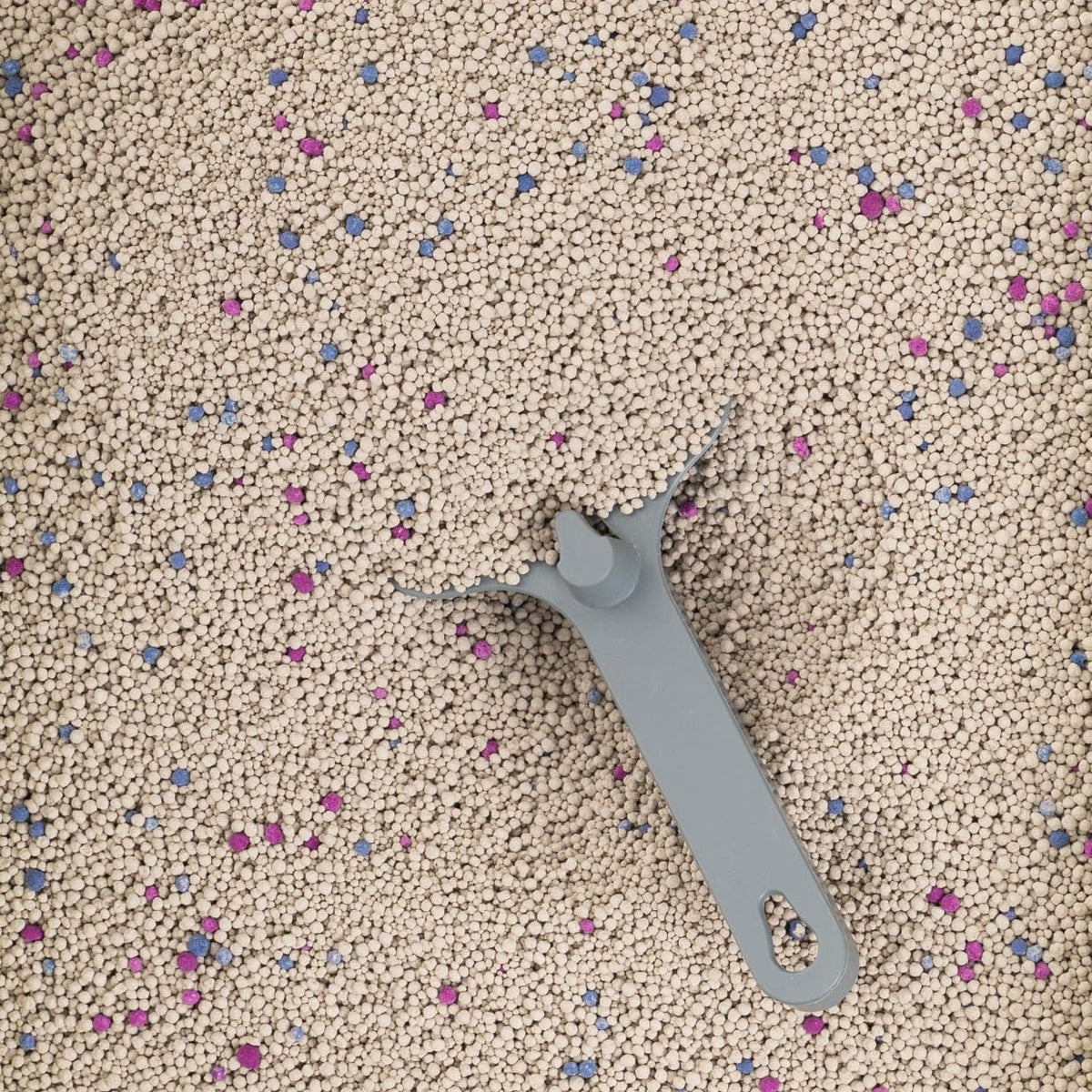 Close-up of Pawfect Lavender Bentonite Cat Litter granules with a grey scoop.
